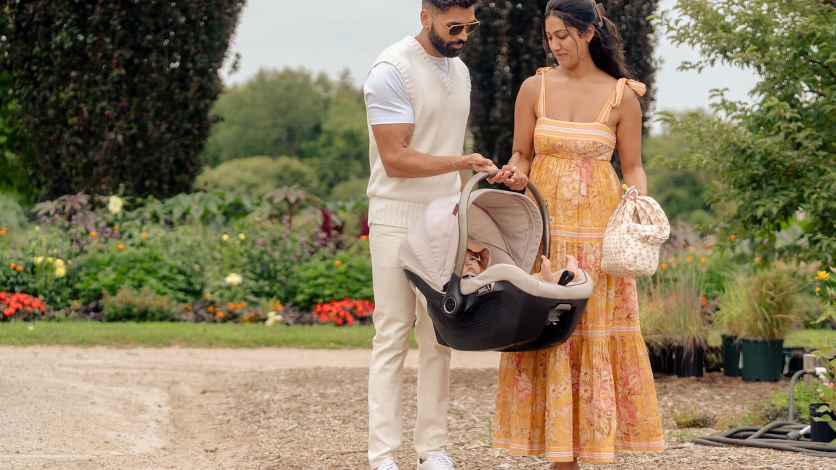 mother and father carrying baby in infant car seat