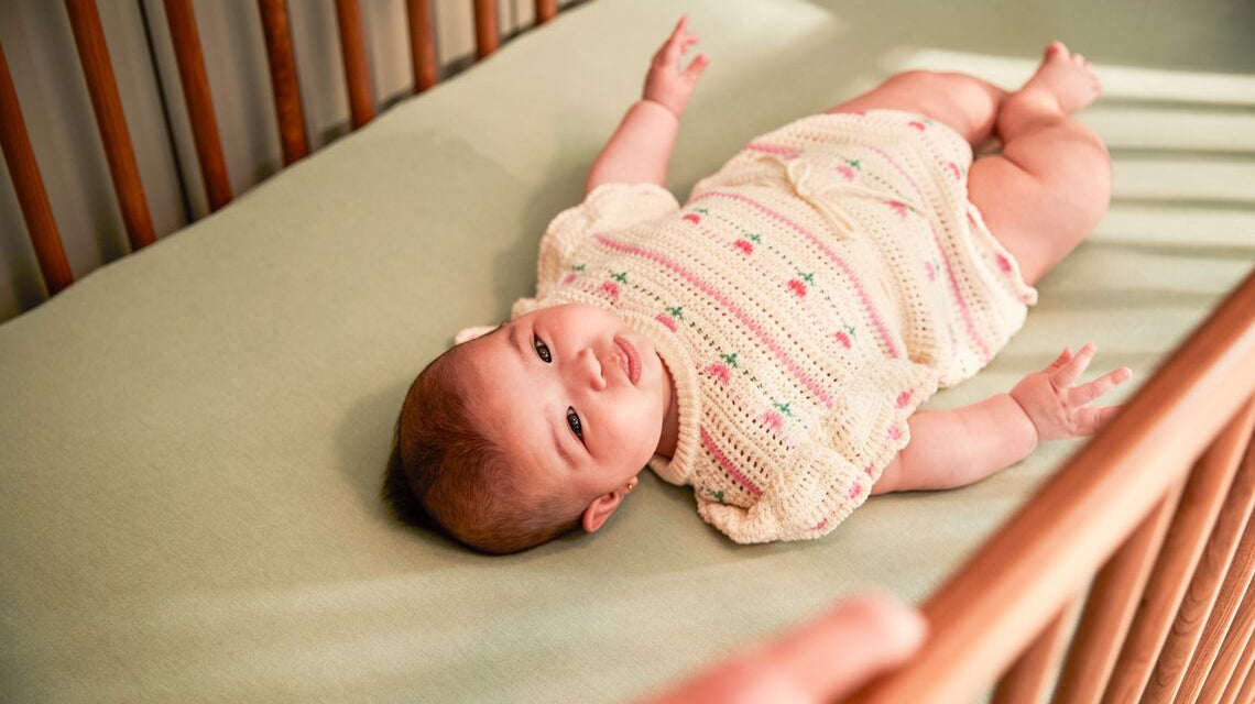 Baby laying on its back in a crib