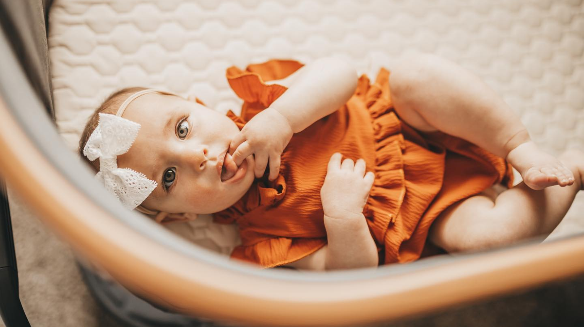 baby in bassinet looking at camera curiously