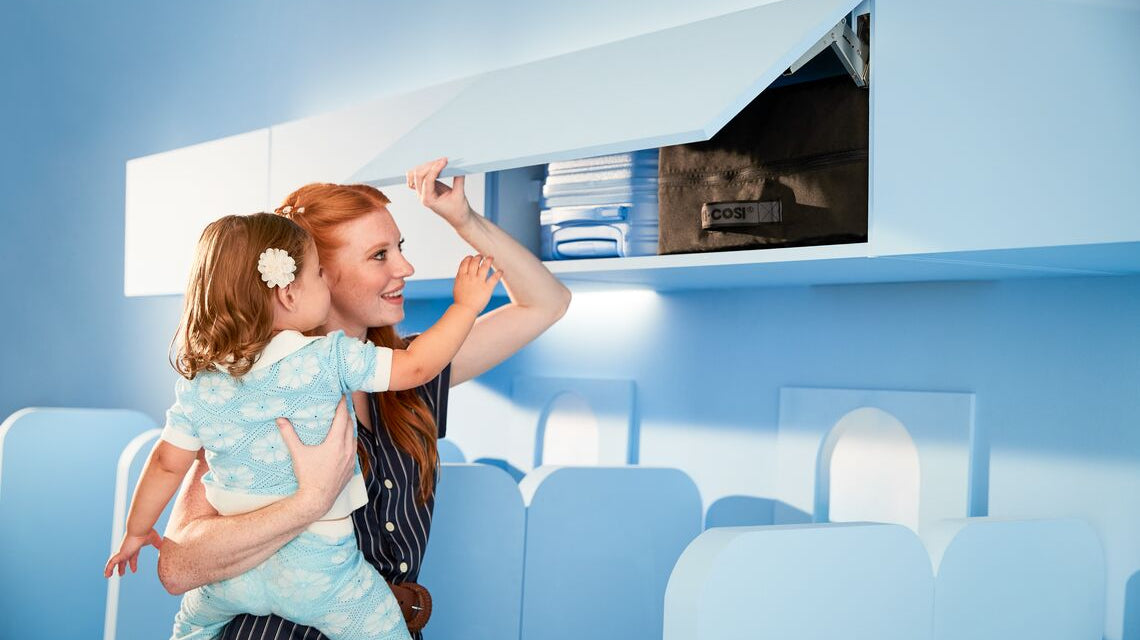 Mom and child looking at stroller in overhead bin on a plane