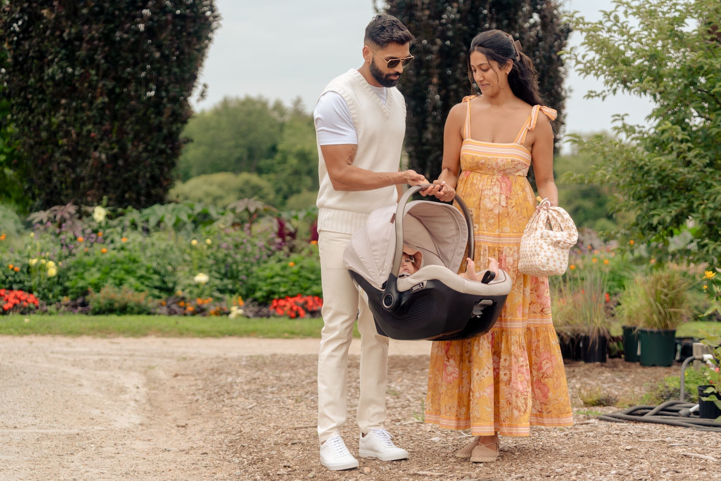 mother and father carrying baby in infant car seat