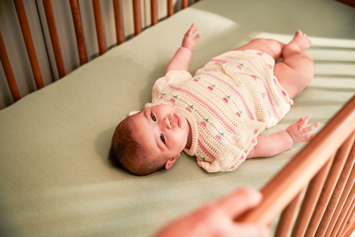 Baby laying on its back in a crib