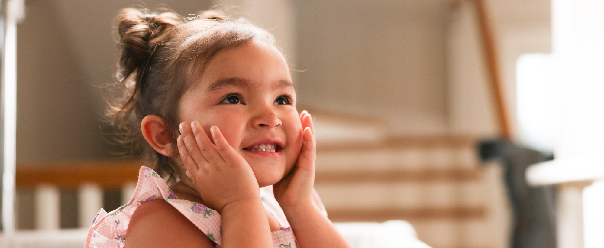 toddler with hands on her face smiling