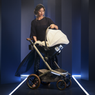 Woman pushing a modern stroller with a baby carrier against a dark blue background