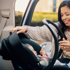 Tayla™ Travel System - mother putting infant in infant car seat in vehicle