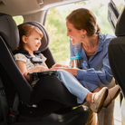 Woman adjusting a child's car seat in a vehicle